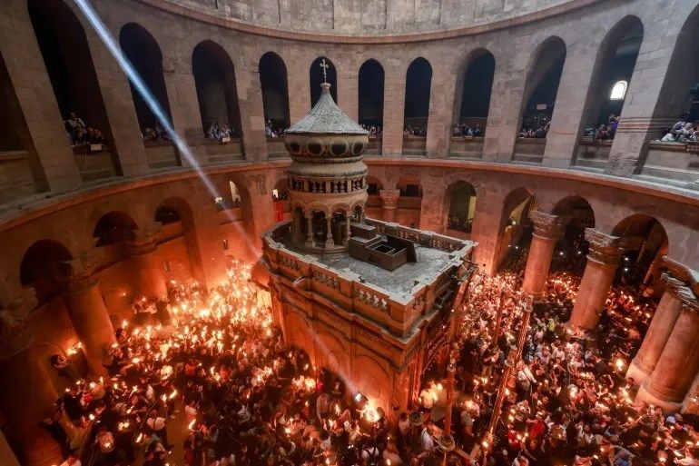 Kaarslicht vult een oude, ronde kerk rond een centraal heiligdom